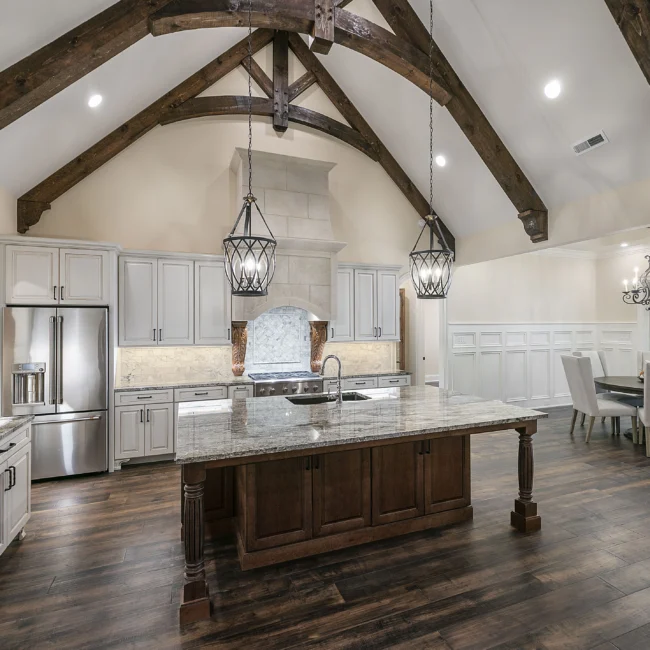 Kitchen with dark wood island, granite top and vaulted timber ceiling in European Villa, a custom home by Mike Stevens Homes