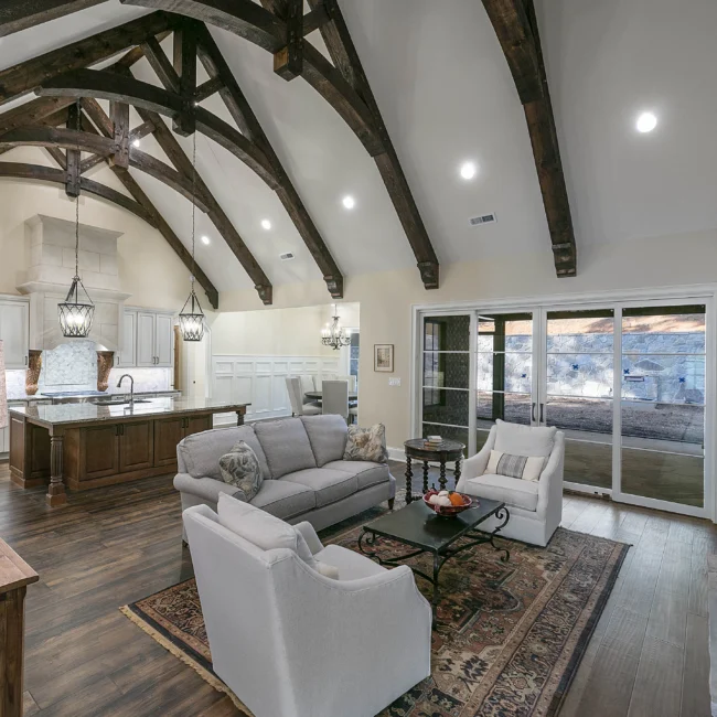 Open family room with sliding glass doors and beamed ceiling in European Villa, a custom home by Mike Stevens Homes