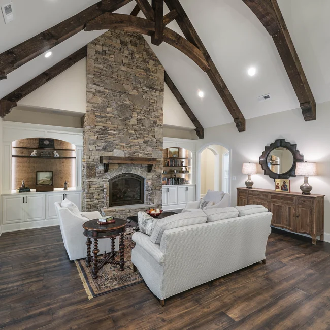 Living room with stone fireplace, built-in niches and timber ceiling in European Villa, a custom home by Mike Stevens Homes