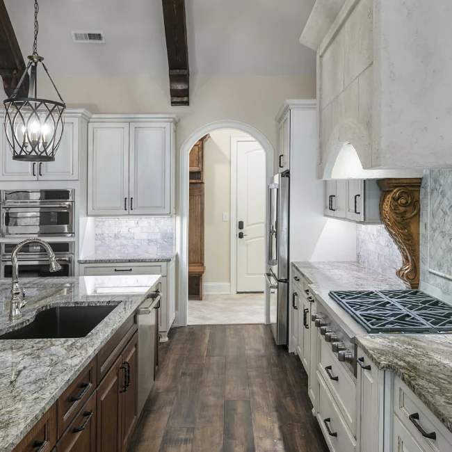 Galley kitchen with cream cabinets, granite counters and arched door in European Villa, a custom home by Mike Stevens Homes