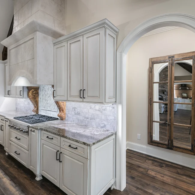 Cream kitchen cabinets with carved corbel and range hood in European Villa, a custom home by Mike Stevens Homes