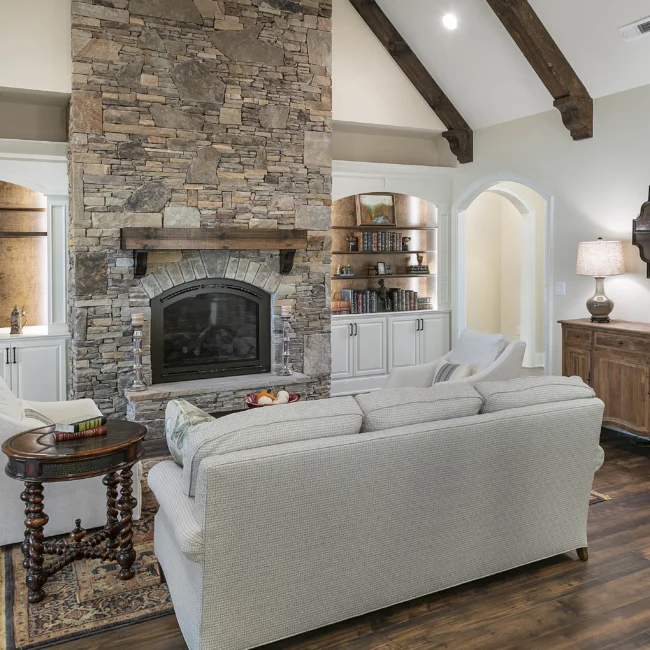 Living room with stone fireplace, sofa and wood side table in European Villa, a custom home by Mike Stevens Homes