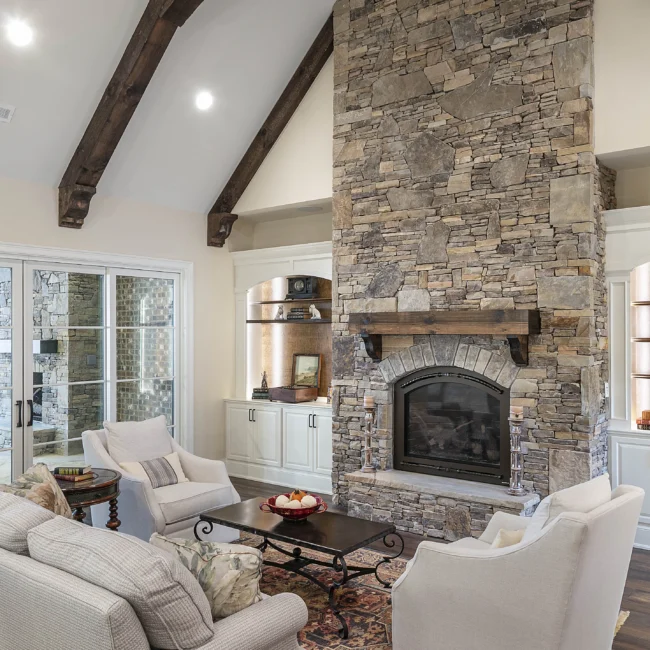 Sitting area with stone fireplace, lounge chairs and sliding doors in European Villa, a custom home by Mike Stevens Homes