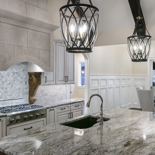 Granite kitchen island with farmhouse sink and iron lantern pendant in European Villa, a custom home by Mike Stevens Homes