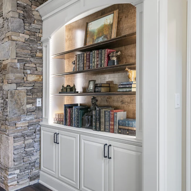 Stone wall with built-in cabinets, wood shelves and framed art in European Villa, a custom home by Mike Stevens Homes