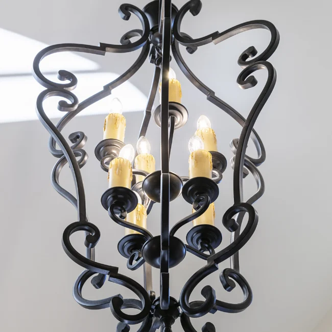 Close-up of ornate black iron chandelier with scrolled arms in European Villa, a custom home by Mike Stevens Homes