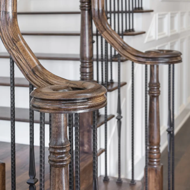 Curved wood handrail and twisted iron balusters on a staircase in European Villa, a custom home by Mike Stevens Homes