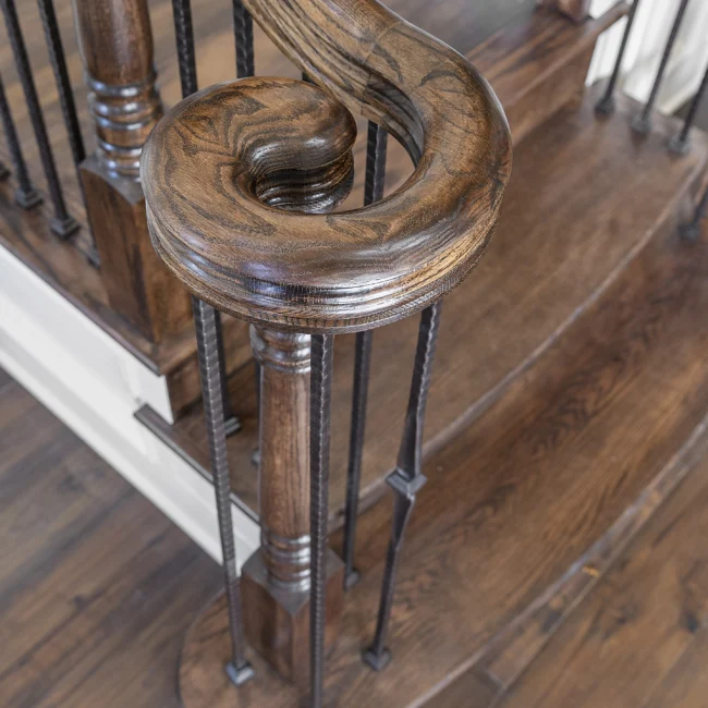 Close-up of carved wood newel post and curved handrail in European Villa, a custom home by Mike Stevens Homes