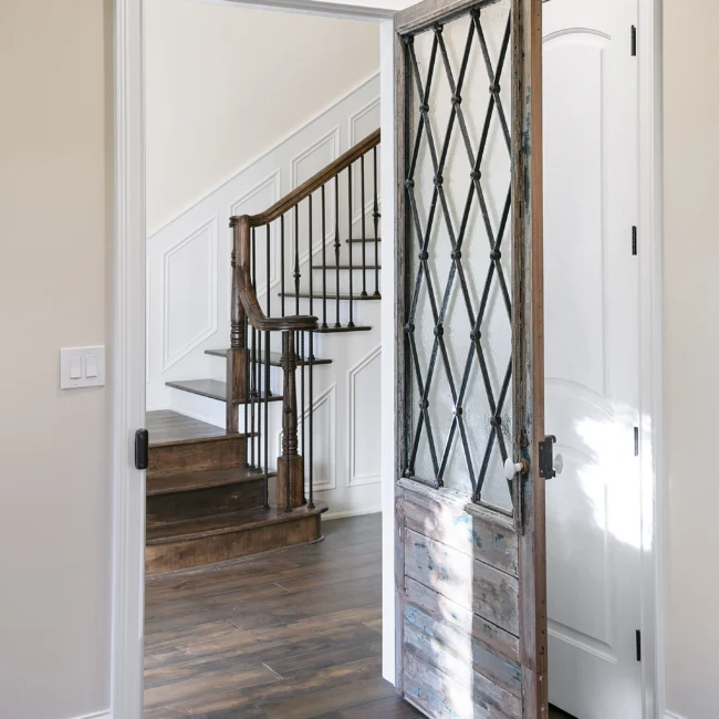 Staircase beside a wrought iron lattice door with wood floors in European Villa, a custom home by Mike Stevens Homes