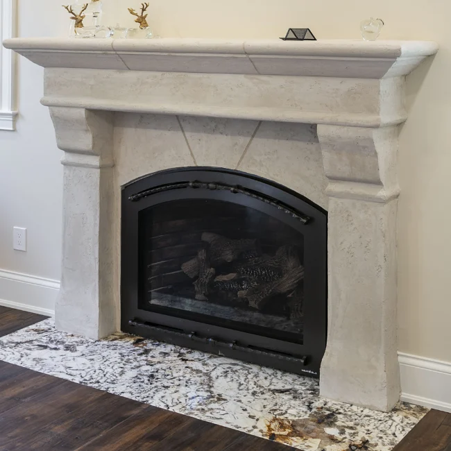 Limestone fireplace mantel with black firebox and marble hearth in European Villa, a custom home by Mike Stevens Homes