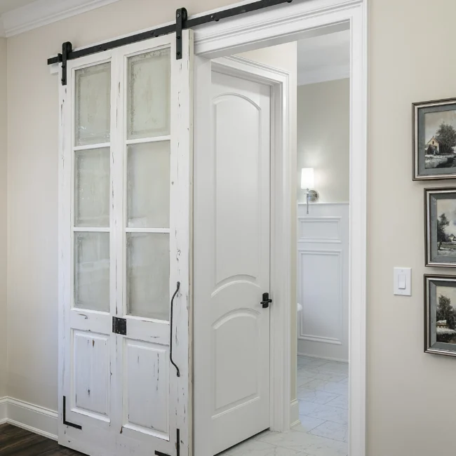 Barn door with glass panes and white paneled door in European Villa, a custom home by Mike Stevens Homes