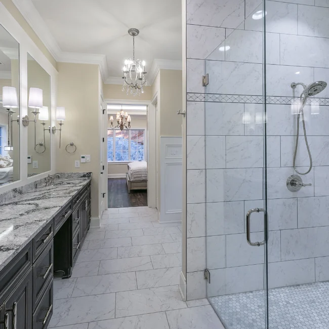 Marble-tiled walk-in shower with glass door in European Villa, a custom home by Mike Stevens Homes