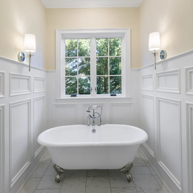 Clawfoot soaking tub with wainscoting and wall sconces in European Villa, a custom home by Mike Stevens Homes