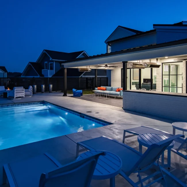 Pool and covered patio with blue lounge seating at twilight in Urban Oasis by Mike Stevens Homes