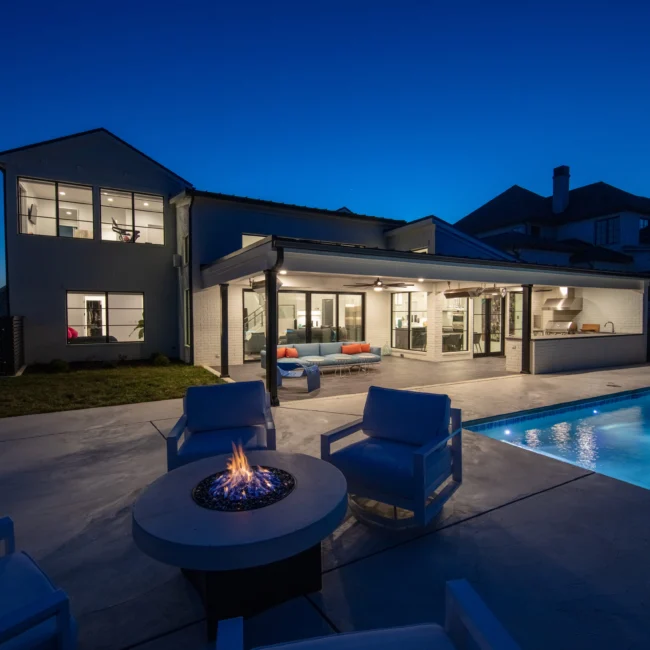 Back patio at dusk with fire pit, lounge chairs and pool in Urban Oasis by Mike Stevens Homes