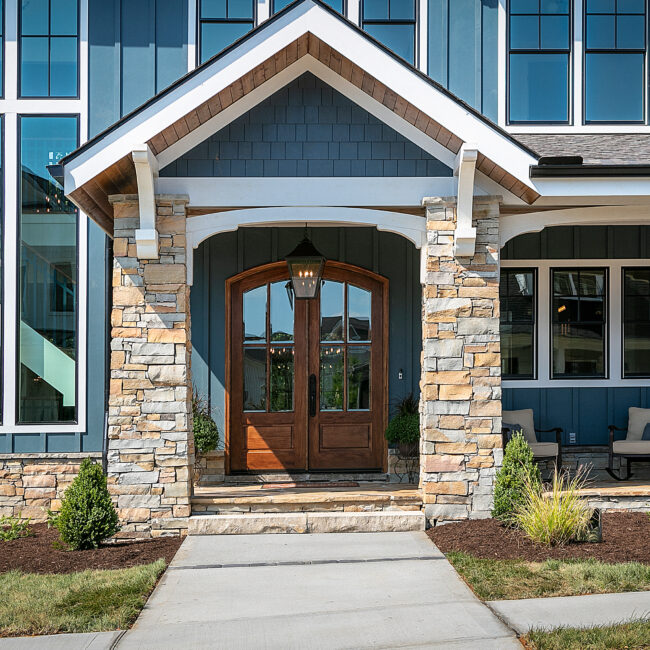 Arched wood double front doors framed by stone columns in Southern Belle, a custom home by Mike Stevens Homes