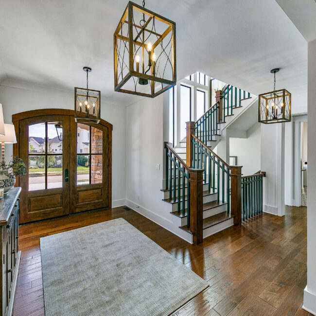 Foyer with iron chandelier, French doors and wood-tread staircase in Southern Belle, a custom home by Mike Stevens Homes