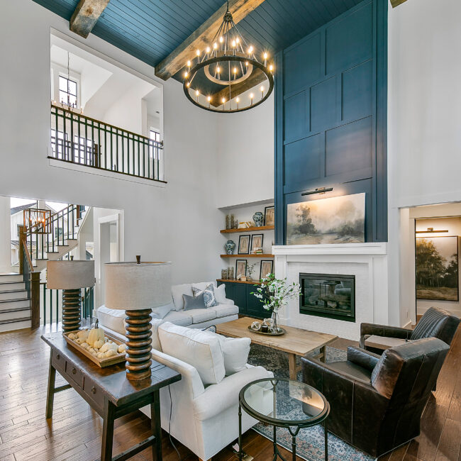 Living room with blue paneled wall and stone fireplace in Southern Belle, a custom home by Mike Stevens Homes