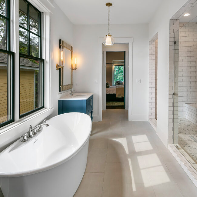 Freestanding tub under windows beside a glass-enclosed shower in Southern Belle, a custom home by Mike Stevens Homes