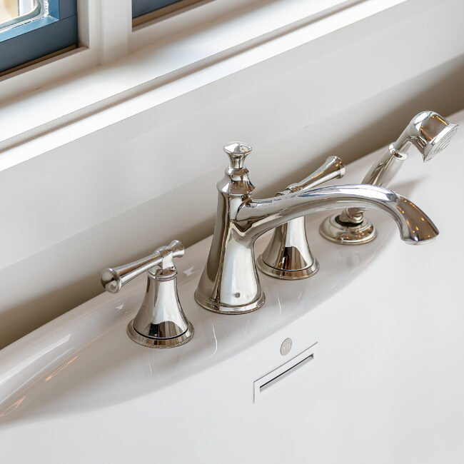 Close-up of brushed nickel deck-mount tub faucet and handheld shower in Southern Belle, a custom home by Mike Stevens Homes