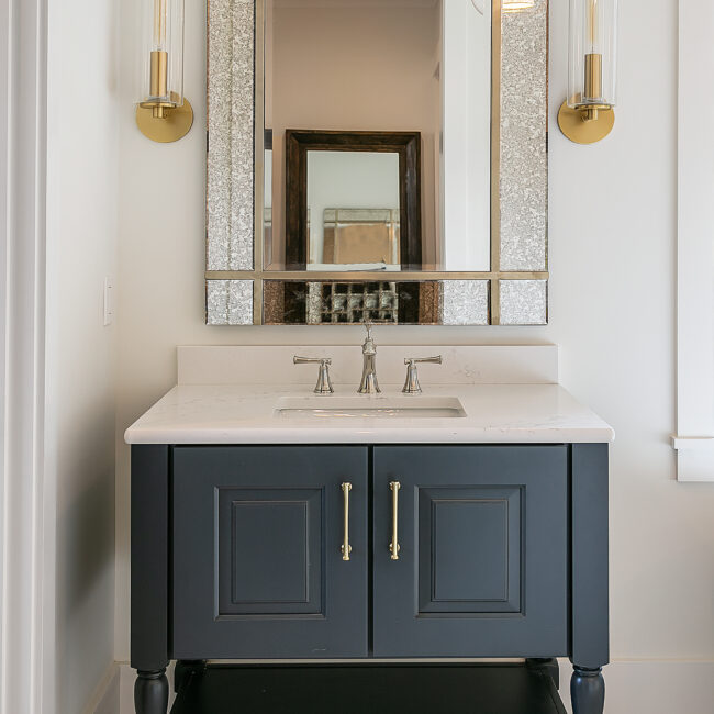 Navy vanity with brass pulls, quartz top and framed mirror in Southern Belle, a custom home by Mike Stevens Homes