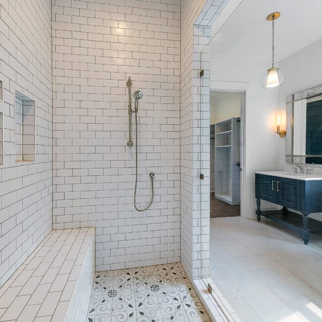 Shower with subway tile, patterned floor and handheld showerhead in Southern Belle, a custom home by Mike Stevens Homes
