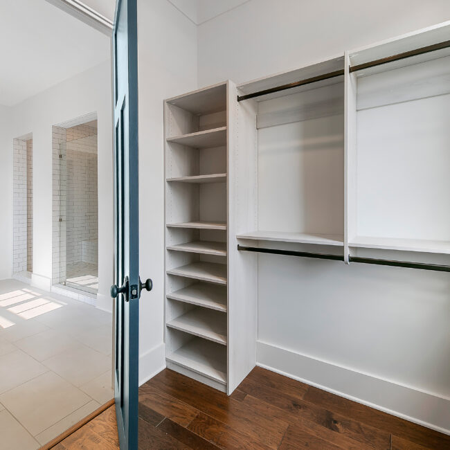 Walk-in closet with open shelving, hanging rods and wood floors in Southern Belle, a custom home by Mike Stevens Homes