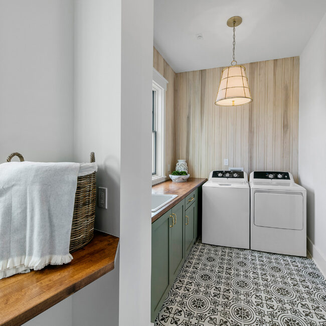 Laundry room with wood-paneled wall and patterned tile floor in Southern Belle, a custom home by Mike Stevens Homes