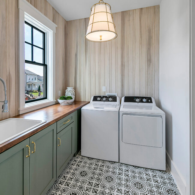 Laundry room with green cabinets, wood countertop and washer and dryer in Southern Belle, a custom home by Mike Stevens Homes