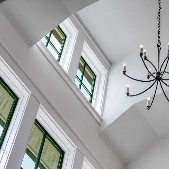 Two-story stairwell with chandelier and tall windows in Southern Belle, a custom home by Mike Stevens Homes