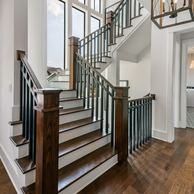 Staircase with dark spindles, wood newel post and hardwood steps in Southern Belle, a custom home by Mike Stevens Homes