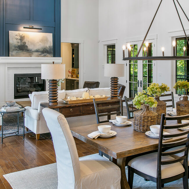 Dining room with farmhouse table, upholstered chairs and fireplace in Southern Belle, a custom home by Mike Stevens Homes