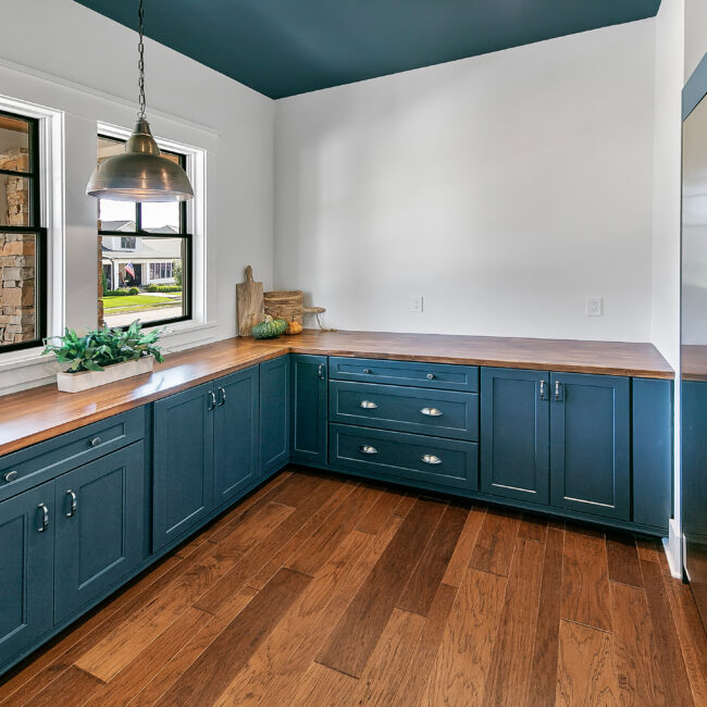 Kitchen with teal cabinets, butcher-block counter and corner window in Southern Belle, a custom home by Mike Stevens Homes