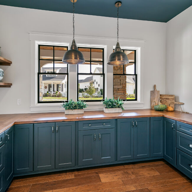 Teal lower cabinets with wood countertop and view through windows in Southern Belle, a custom home by Mike Stevens Homes