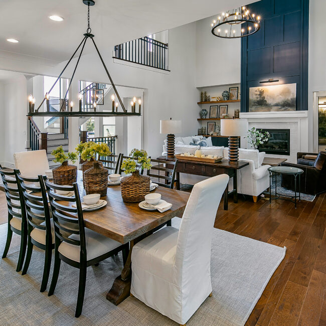 Dining table with pendant lights, open to living room and fireplace in Southern Belle, a custom home by Mike Stevens Homes