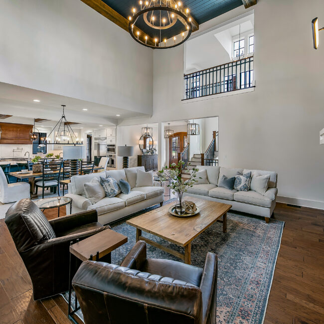 Open great room with leather chairs, sofas and high ceiling in Southern Belle, a custom home by Mike Stevens Homes