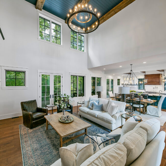 Open living room with cream sofas, coffee table and high ceiling in Southern Belle, a custom home by Mike Stevens Homes