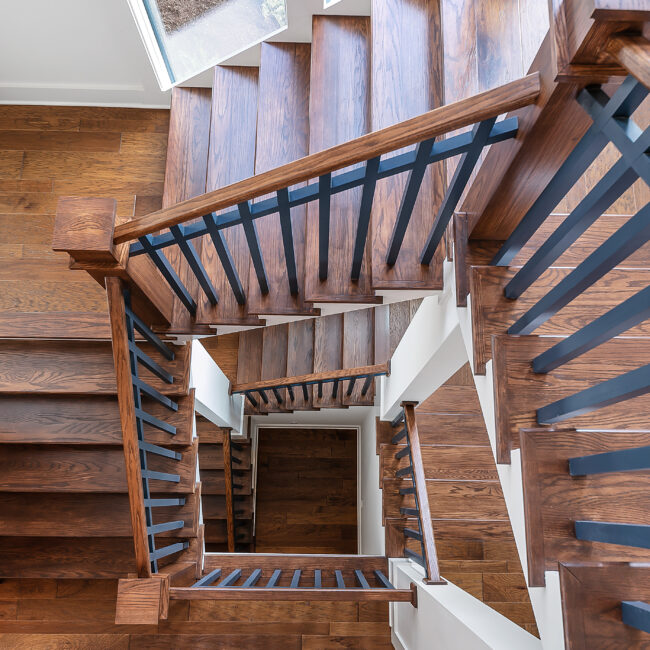 Looking up a spiral wood staircase with iron rail in Southern Belle, a custom home by Mike Stevens Homes