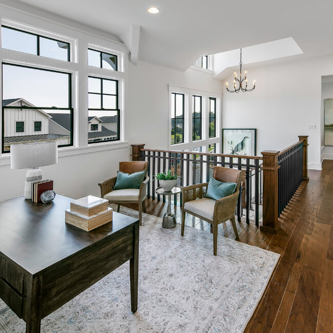 Upstairs loft office with wood desk, armchairs and skylight in Southern Belle, a custom home by Mike Stevens Homes