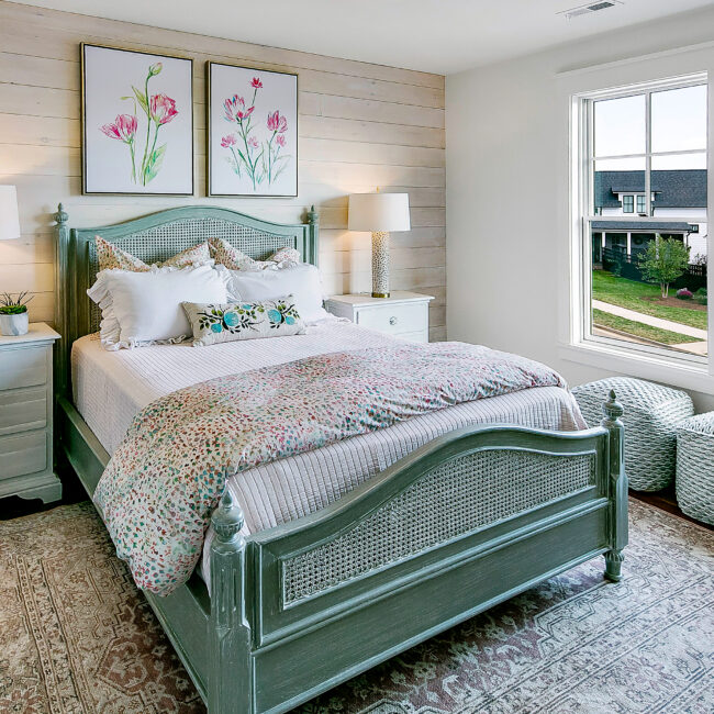 Bedroom with sage green bed frame and wood floors in Southern Belle, a custom home by Mike Stevens Homes