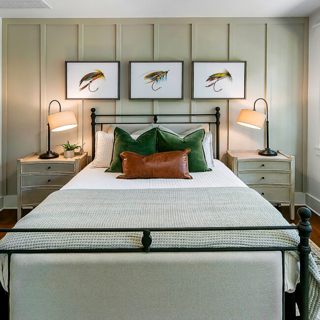 Bedroom with fly fishing prints, green bedding and board wall in Southern Belle, a custom home by Mike Stevens Homes
