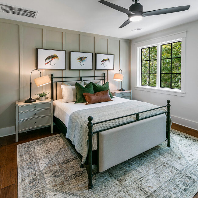 Bedroom with board-and-batten wall and dark iron bed in Southern Belle, a custom home by Mike Stevens Homes