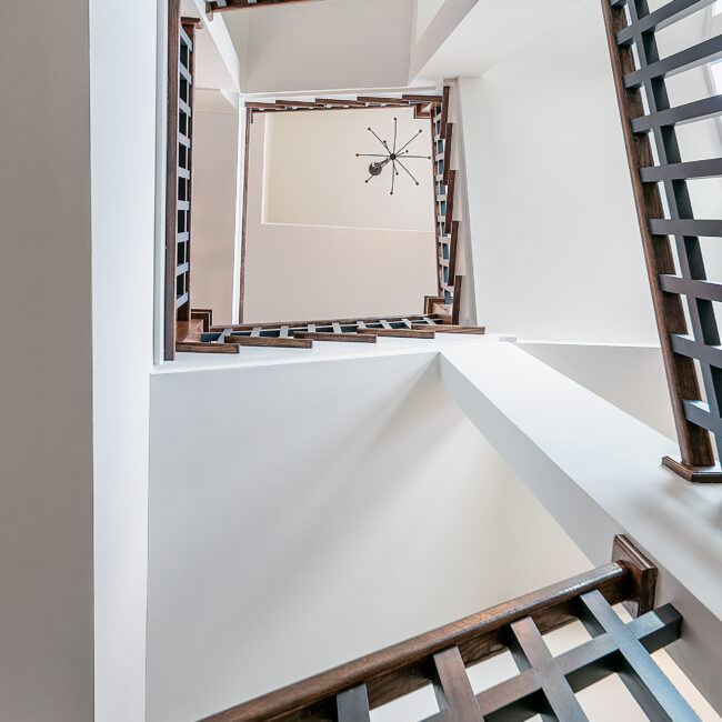 Close-up of wood stair railing and white ceiling beam in Southern Belle, a custom home by Mike Stevens Homes