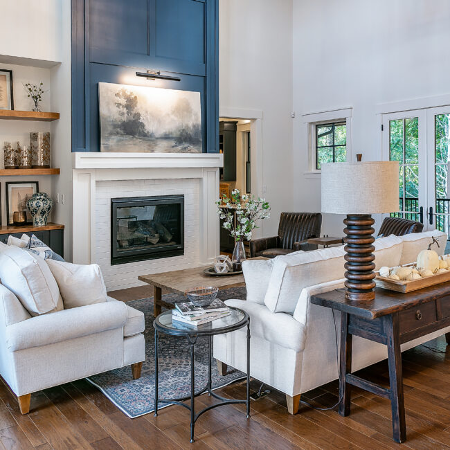 Living room with dark blue fireplace wall and white sofas in Southern Belle, a custom home by Mike Stevens Homes