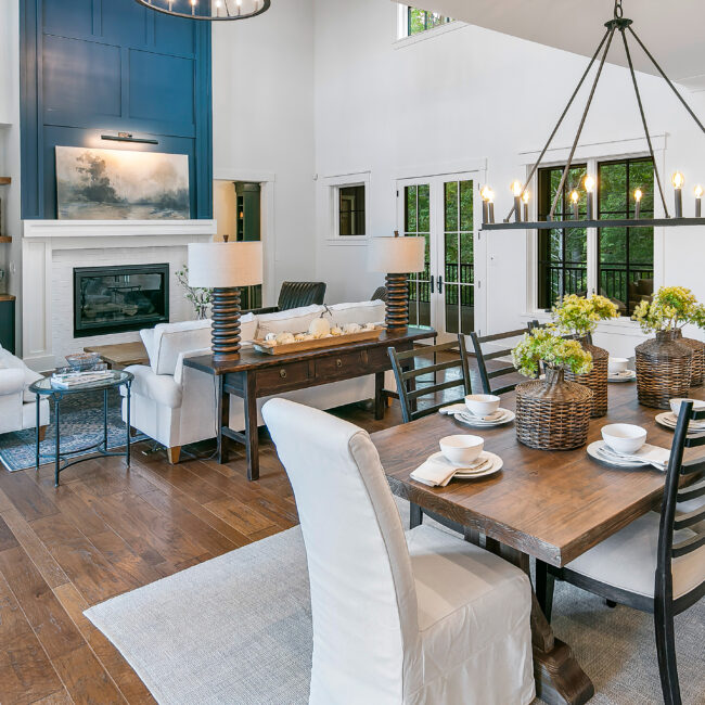 Dining room with farm table and living room fireplace beyond in Southern Belle, a custom home by Mike Stevens Homes