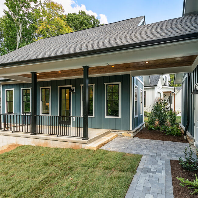 Covered back porch with stone patio, lawn and blue-gray siding in Southern Belle, a custom home by Mike Stevens Homes