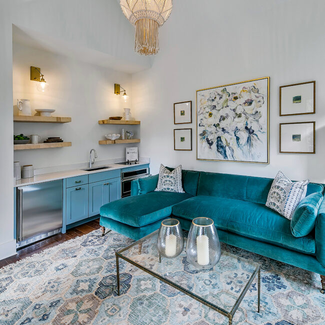 Living room with teal velvet sectional, wet bar and floating shelves in Southern Belle, a custom home by Mike Stevens Homes