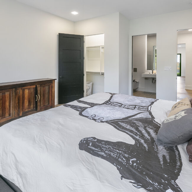 Bedroom with gray graphic bedding and walnut dresser in Rocky Top Hideaway, a custom home by Mike Stevens Homes
