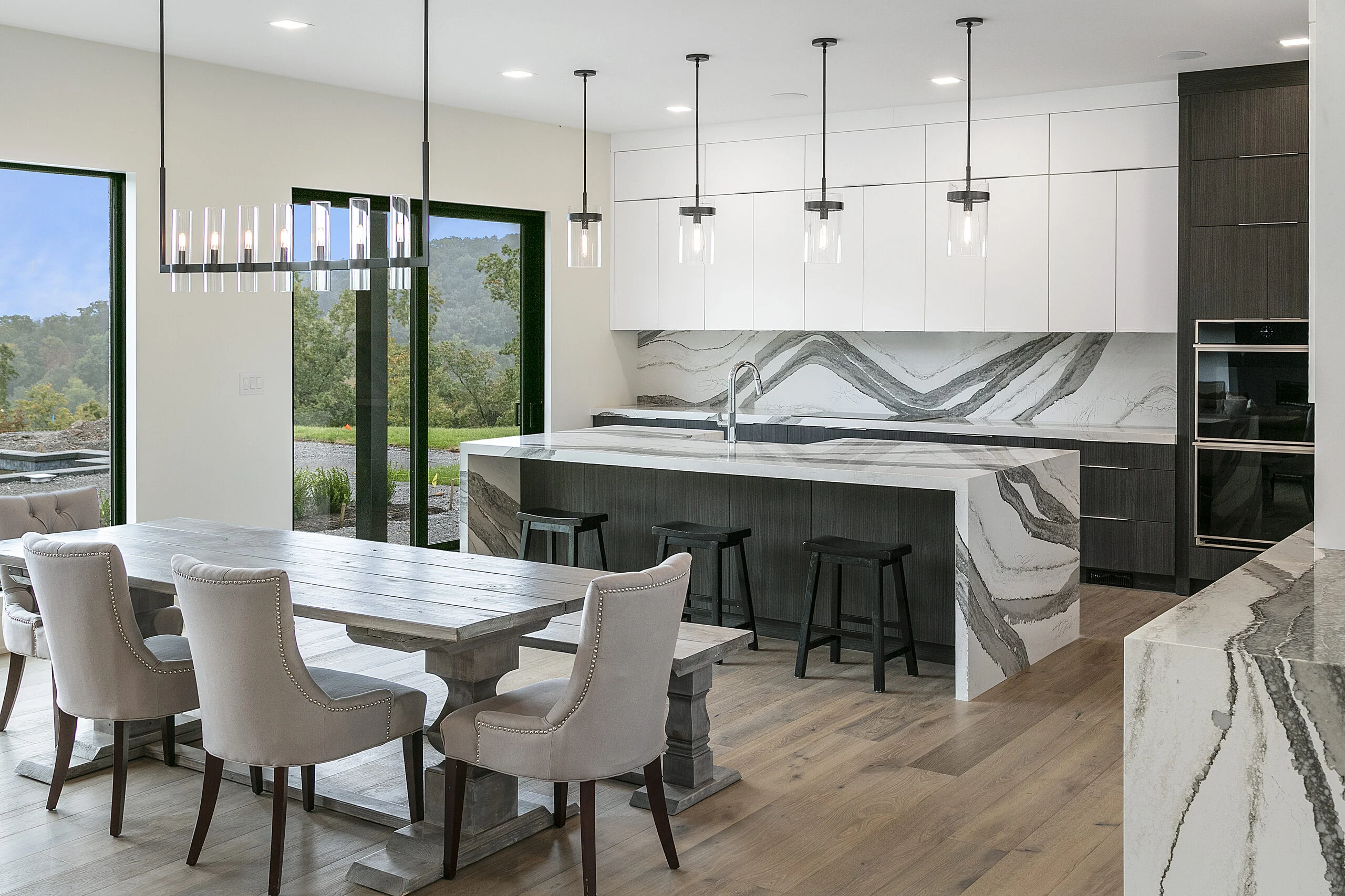 Kitchen island with black stools and glass doors to the view in Rocky Top Hideaway, a custom home by Mike Stevens Homes