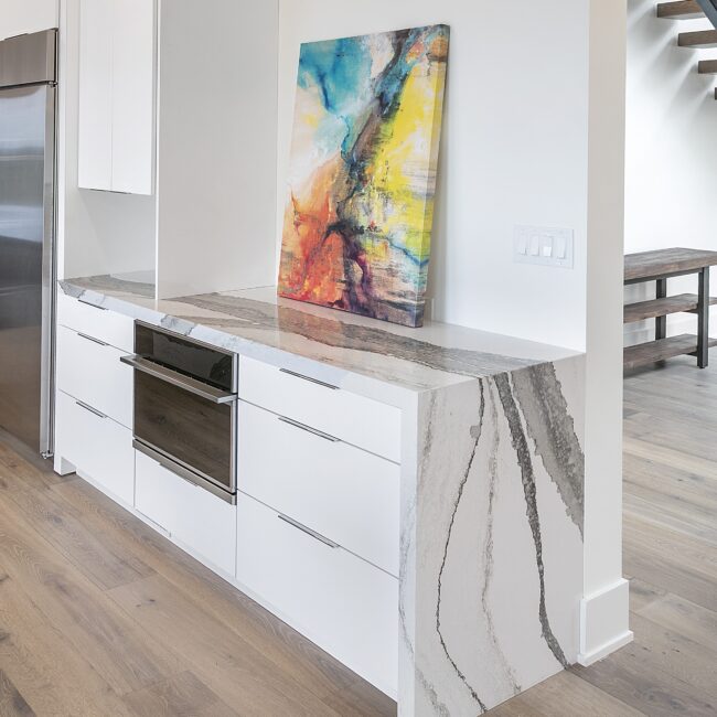 Built-in wall oven under veined quartz counter in Rocky Top Hideaway, a custom home by Mike Stevens Homes